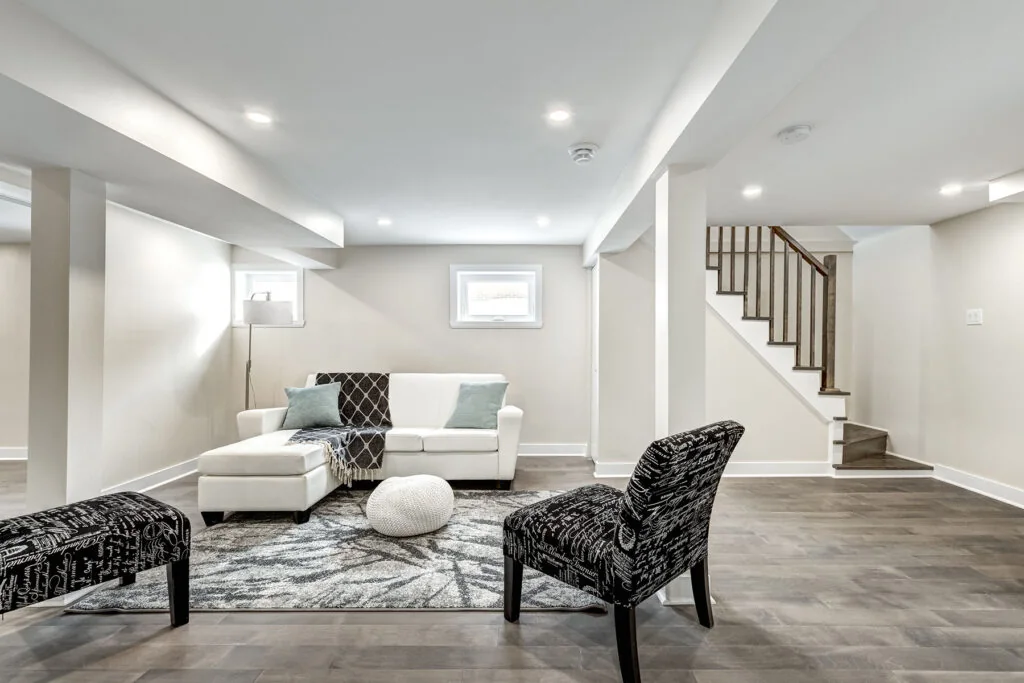 Finished basement living area with seating and natural light