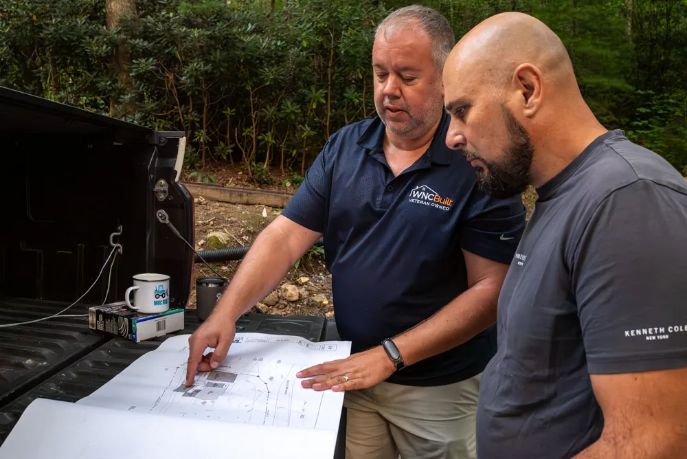 Brad Currin reviewing project plans on a truck tailgate at a wooded jobsite