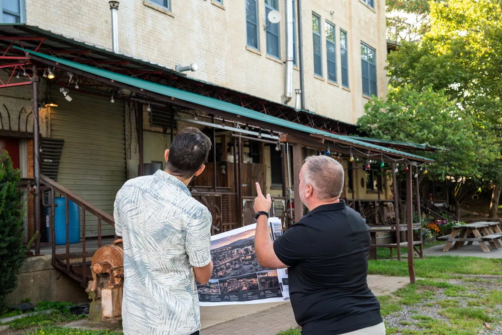 Brad Currin holding a renovation rendering in front of an older commercial building