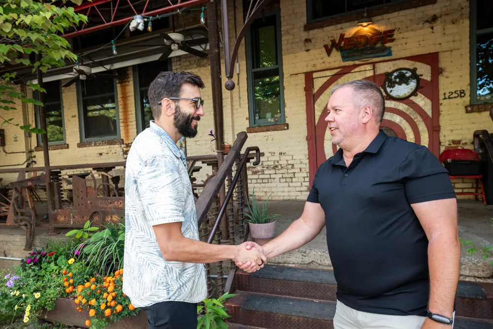 Brad Currin shaking hands outside a project building